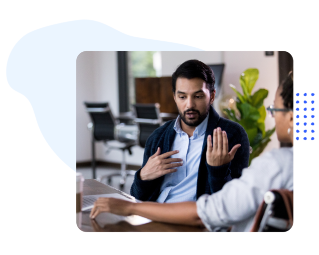 Two people having a discussion at a conference table in an office